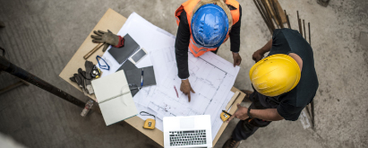 Overhead view of construction workers around a table looking at drawings and plans