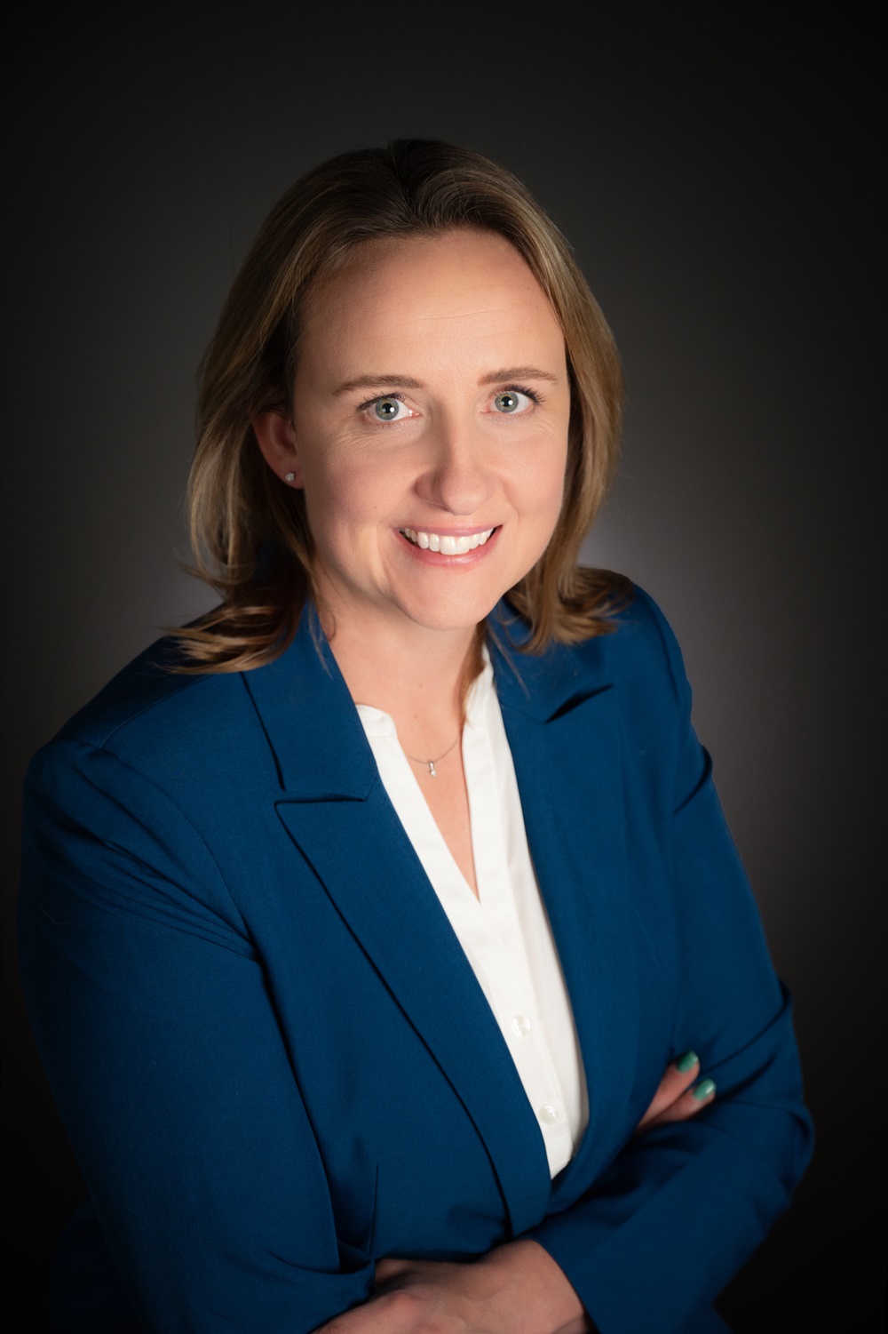 Women wearing blue suit with arms folded and black background