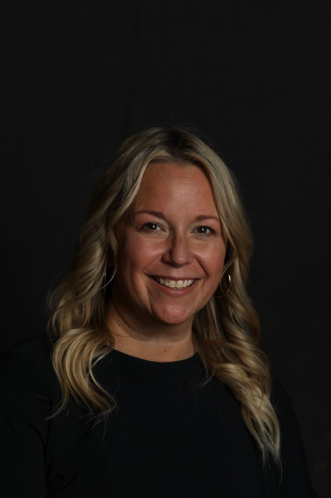 woman, long blond hair, smiling, wearing black, dark background