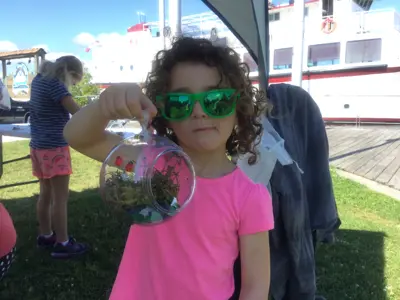 Child holding up a fairy garden they made at an outdoor program.