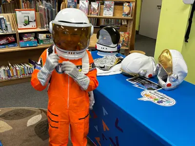 Child in an orange astronaut costume at Science North event.