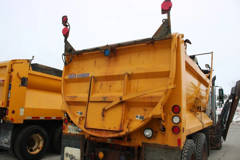 Close up view of the back of a plow truck with a decal that reads Adam Sander