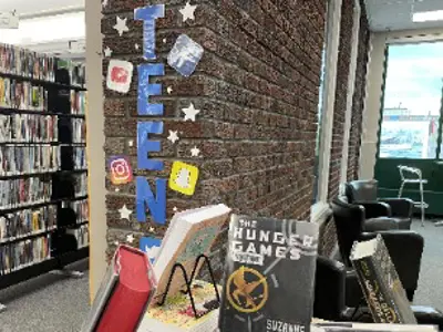 Teen sign on a brick wall and a display of teen books.