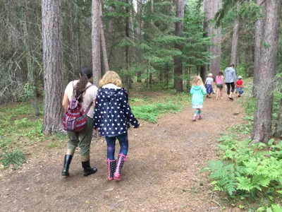 A group of families walking a nature trail during outdoor programming.
