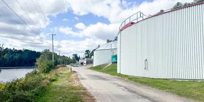 [Exterior image of roadway going to Wastewater Treatment Plant, showing sunny day and two aeration tanks.] 