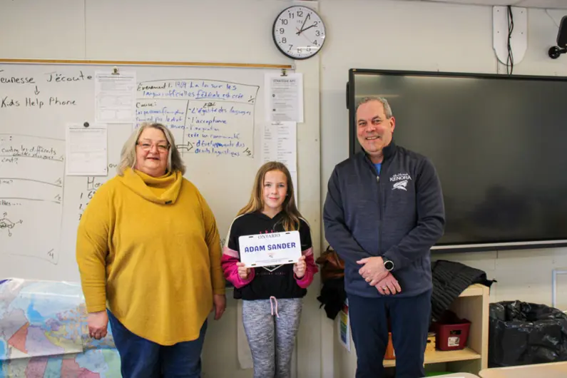 Two members of City Council awarding student with contest keepsake