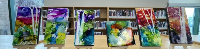 Ceramic tiles painted with alcohol ink depicting birch trees at sunset.
